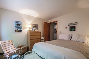 Ein Schlafzimmer mit einem Bett, einem Holzstuhl, einem Schminktisch und einer Lampe.