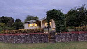 Una casa de un piso con un muro de piedra y un pequeño porche.