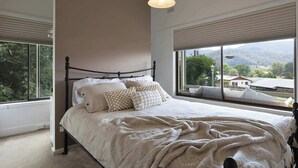 Un dormitorio con una cama grande, vistas al exterior a través de una ventana y una lámpara en el techo.