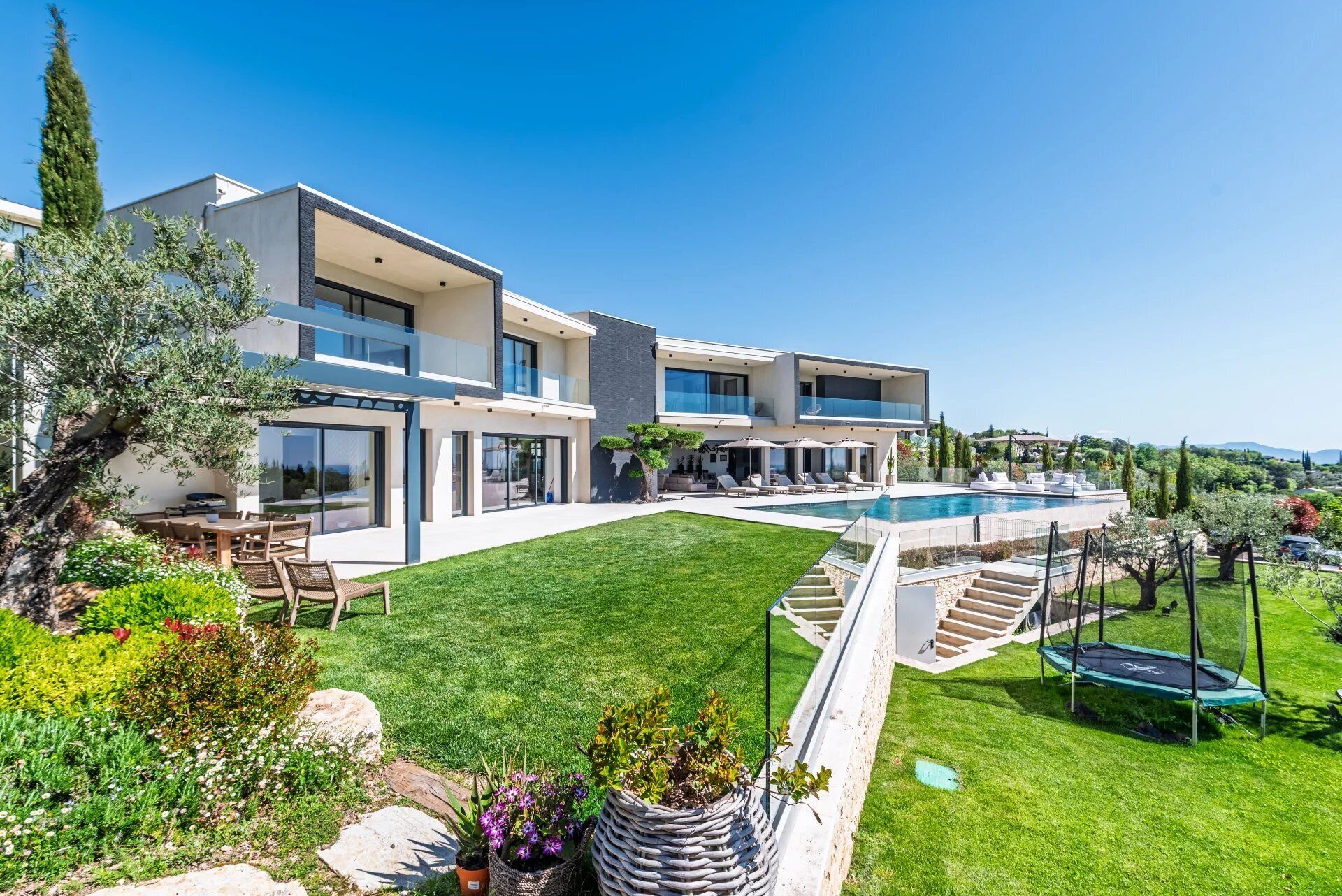 Une maison moderne à deux étages, dotée d’une grande piscine, d’un espace extérieur aménagé et d’un jardin bien entretenu.