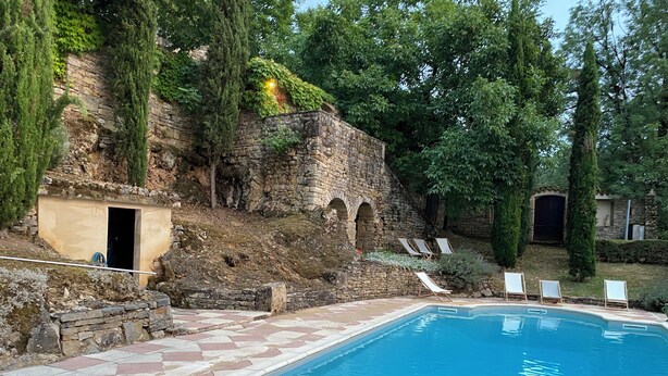 A swimming pool with a stone wall and a small door, surrounded by trees and a few lounge chairs. - House 160 m2 on 6000 m2, sleeps 12 Private garden + shared swimming pool (Espinas)