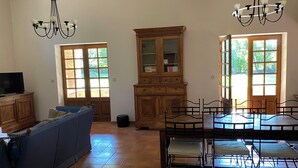 A spacious living room with a blue sofa, a wooden cabinet, and a dining area with a table and chairs. - House 160 m2 on 6000 m2, sleeps 12 Private garden + shared swimming pool (Espinas)