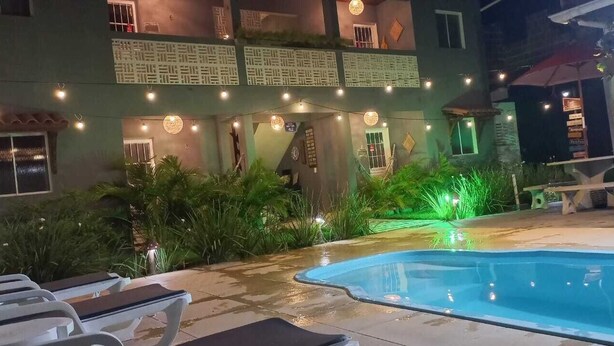 A pool area with lounge chairs and a building with balconies. - CHALES DO TOQUE (São Miguel dos Milagres)