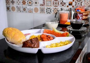 Un plato blanco con un sándwich, carne, zanahorias y huevos.