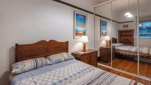 A bedroom with a wooden bed, a nightstand, a mirror, and a poster on the wall.
