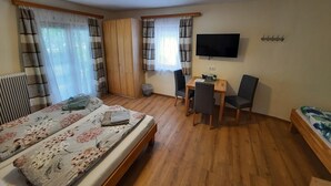 A bedroom with a bed, a desk, two chairs, a TV, and a wardrobe. - Kirchenwirt Halbwax (Kaumberg)