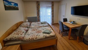 A room with a bed, a desk, a chair, a television, and a radiator. - Kirchenwirt Halbwax (Kaumberg)