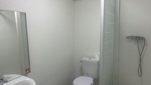 Une salle de bain avec un lavabo blanc, des toilettes et une douche à parois en verre.
