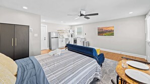 A modern hotel room with a bed, a desk, and a kitchenette. - Spacious studio unit in the heart of the Highlands (Louisville)