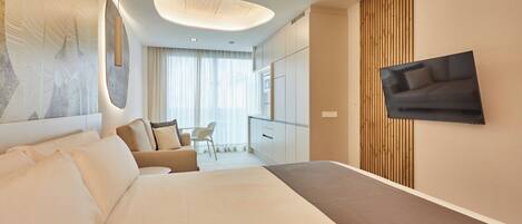 Une chambre d’hôtel moderne avec un grand lit, un téléviseur fixé au mur et un coin repas à l’arrière-plan.