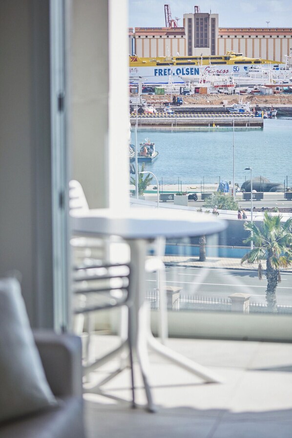 A balcony with a view of a marina, including boats and a building with 'FREI. OLSEN' signage.