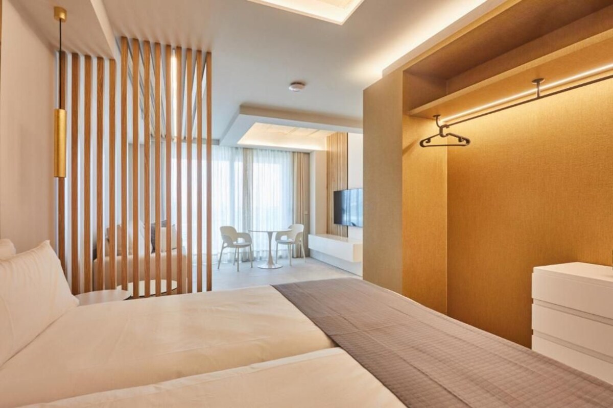 Ein modernes Hotelzimmer mit einem großen Bett, einem Schreibtisch und einem Fernseher.