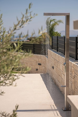 A modern outdoor water feature with a metal structure and a stone wall.