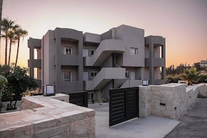 A modern multi-story building with a unique architectural design, featuring balconies and a central staircase.