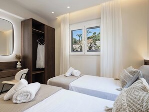 A hotel room with two beds, a desk, and a wardrobe. - Kymélia Ground Suite With Private Pool & SeaView (Galatas)