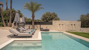 A swimming pool with lounge chairs and umbrellas, surrounded by stone walls and palm trees. - Kymélia Ground Suite With Private Pool & SeaView (Galatas)