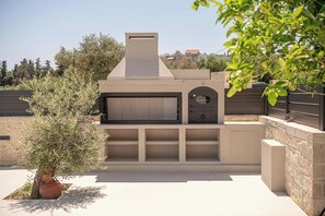 An outdoor kitchen area with a built-in oven and seating space. - Kymélia Ground Suite With Private Pool & SeaView (Galatas)