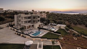Un edificio moderno de varios pisos con piscina, mobiliario exterior y un jardín ajardinado.
