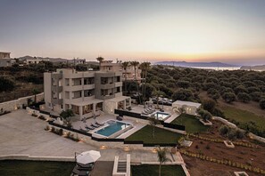 A modern multi-story building with a pool, outdoor seating, and a landscaped garden.