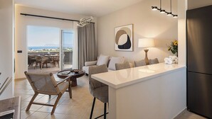 Una cocina moderna con una isla central, un comedor con sillas de mimbre, un sofá y vistas al exterior.