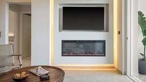 Una sala de estar moderna con chimenea, televisor de pantalla plana montado sobre ella y un área de estar cómoda con sofá y una mesita de centro.