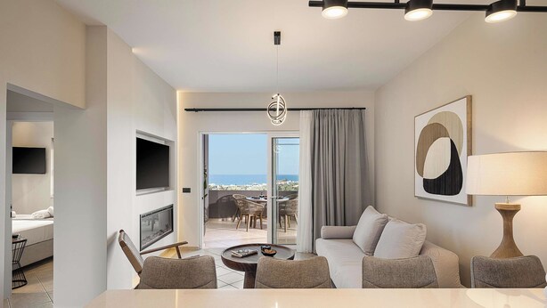 Une chambre d’hôtel moderne dotée d’un balcon, d’un téléviseur à écran plat, d’un canapé, d’une table à manger et d’une lampe.