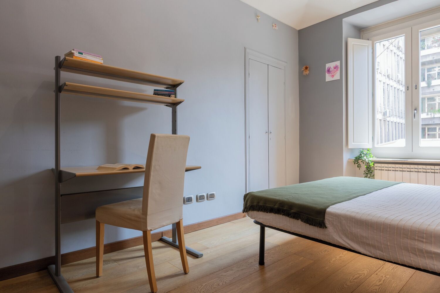 Une chambre à coucher avec un lit, un bureau et une chaise, une fenêtre et une porte.