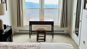 A bedroom with a large bed, a wooden bench, a desk, and a window with curtains. - Beech Mountain Condo w/ spectacular views & close proximity to hiking and skiing (Beech Mountain)