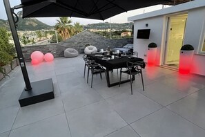 An outdoor patio with a table set for dining, a black umbrella, and a view of the landscape. - Ac Luxury Penthouse - private terrace (Meta)