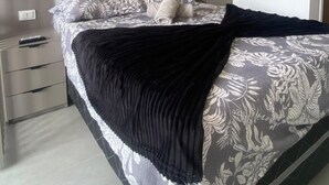 A bedroom with a bed, a bedside table, a wardrobe, and an air conditioning unit.