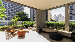 Terraza en la azotea con sillones de sol, plantas en macetas y vistas a edificios de la ciudad.