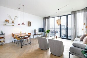A modern living room with a dining area, large windows, and a city view. - Hellingstraat type 2 (AMSTERDAM)