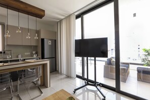 A modern kitchen with a dining area, a large window with a view, and a mounted television.