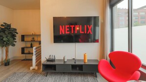 Uma sala de estar moderna com uma televisão de tela plana grande fixada na parede exibindo "NETFLIX".