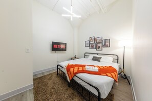 A bedroom with a bed, a TV displaying 'NETFLIX', a lamp, and framed pictures on the wall. - Spacious 5BR Luxury Suite Near McCormick Place, Soldier Field & Grant Park (Chicago)