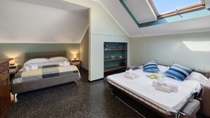 Een slaapkamer met twee bedden, dakraam, nachtkastje en een wandplank.