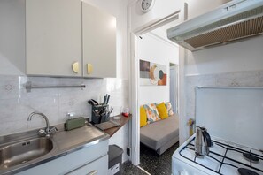 Een kleine keuken met een spoelbak, fornuis en een klein aanrecht met keukengerei.
