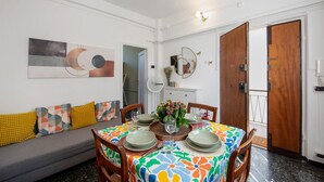 Een eethoek met een ronde tafel, stoelen, een bank en een spiegel aan de muur.
