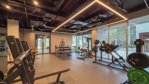 A modern gym with various exercise equipment, large windows, and a clean, spacious layout.