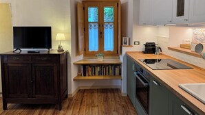 A modern kitchen with wooden countertops, a built-in oven, and a window with decorative curtains. - La Chintana (Ceres)
