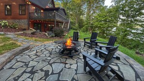 A log cabin with a deck, stone patio, outdoor seating, and a fire pit. - Blessing by the Lake | Lakeside Cabin|Hot Tub Wifi (Scottsville)