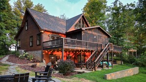 A log cabin with a balcony, outdoor seating, and a stone fire pit. - Blessing by the Lake | Lakeside Cabin|Hot Tub Wifi (Scottsville)