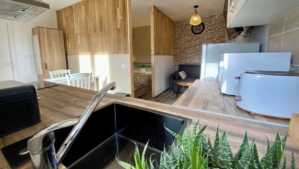 A modern kitchen with a wooden countertop, a sink, a toaster, and a clock on the wall. - STUDIO 263 "Studio with Provencal charm in Suze-la-Rousse - Calm & authenticity (Suze-la-Rousse)