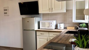 A modern kitchen with white cabinets, a stainless steel refrigerator, a microwave, and a built-in oven. - STUDIO 263 "Studio with Provencal charm in Suze-la-Rousse - Calm & authenticity (Suze-la-Rousse)