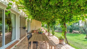 A wooden table and chairs under a vine-covered pergola on a brick patio. - Bed and Breakfast 'Manon' with Shared Terrace, Shared Garden and Wi-Fi (Estézargues)