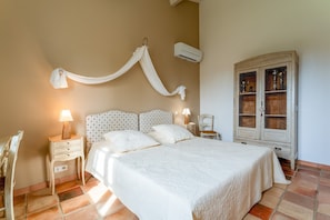 A bedroom with a bed, bedside tables, a chair, an air conditioning unit, and a cabinet. - Bed and Breakfast 'Manon' with Shared Terrace, Shared Garden and Wi-Fi (Estézargues)