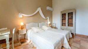 A bedroom with a large bed, a nightstand, a chair, a cabinet, and an air conditioning unit. - Bed and Breakfast 'Manon' with Shared Terrace, Shared Garden and Wi-Fi (Estézargues)