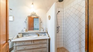 A bathroom with a marble sink, wooden vanity, a mirror with an ornate frame, a shower with white tiles, and a door. - Bed and Breakfast 'Provence' with Shared Terrace, Shared Garden and Wi-Fi (Estézargues)