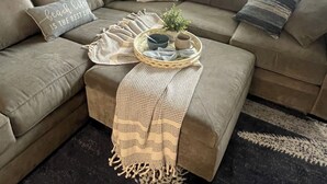 A cozy living room with a large sectional sofa, a woven tray with a plant, and a decorative throw blanket. - Oceanfront condo with private balcony and unobstructed views -Wildwood Crest (Wildwood Crest)