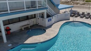A swimming pool with a curved design, a lifeguard station, and lounge chairs on the deck. - Oceanfront condo with private balcony and unobstructed views -Wildwood Crest (Wildwood Crest)